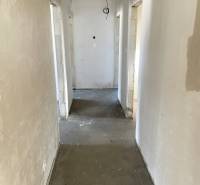 A hallway of a family house with an unfinished ceiling and a concrete floor.
