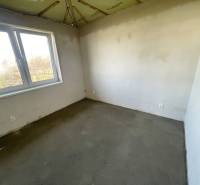 An empty room in a family house with plastered walls and a concrete floor.