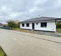 A family house in the village of Soľ with a white-gray facade, surrounded by a paved walkway.