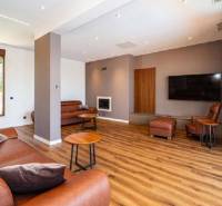 Living room in a villa with wood-patterned flooring, a leather sofa, and a television.