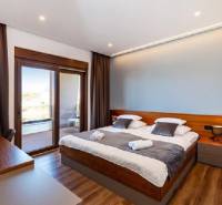 Room with a bed in the villa, floor with wooden decor, balcony with a view.