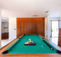 A billiard table in the interior of a villa with a wooden decor floor.