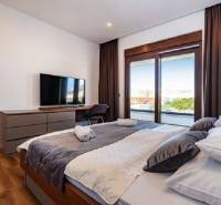 Stylish bedroom with a large bed, television, and wooden decor flooring in the villa.