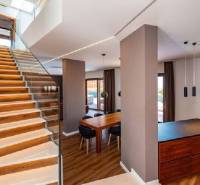 Interior of a villa with wooden flooring, staircase, and dining table.
