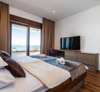 Interior of a villa with a bed, television, and a view of the sea.