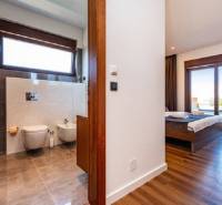 Interior of a villa with wood-decor flooring, bedroom and bathroom with a large window.