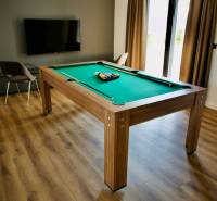 A room in a villa with a billiard table, television, and a wooden decor floor.