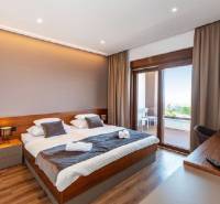 Luxury bedroom in a villa with a balcony, wooden decor flooring, large windows.