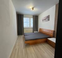 A bedroom with light walls, a double bed, and a floor with a wood decor in a 3-room apartment.