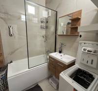 Bathroom with a bathtub, cabinet, and washing machine in a 3-room apartment.