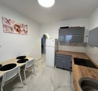 A kitchen in a 3-room apartment with a kitchen unit, table, and wall decoration.