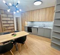 Kitchen and dining room in a 2-room apartment with a wood-patterned floor and shelves.