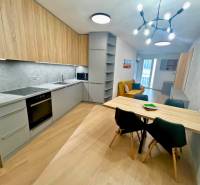 A kitchen in a two-room apartment with a wooden decor floor and a dining table.