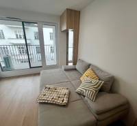 Living room in a two-room apartment with a corner sofa and a balcony, wooden decor flooring.