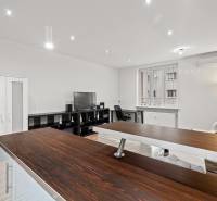 A one-room apartment with a wooden decor floor, equipped with a TV, a desk, and a sofa.