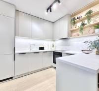A kitchen in a 3-room apartment with white cabinets and a wood-patterned floor.