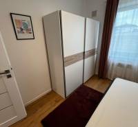 Bedroom in a cozy 2-room apartment on Brečtanová street, light wardrobe, bed, window.