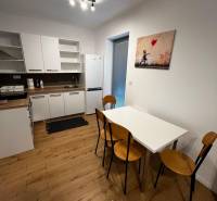 A kitchen with a wooden floor, a white table, and a painting. On Ivy Street, a 2-room apartment.