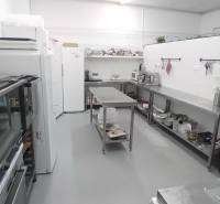 Kitchen equipment in a warehouse hall with stainless steel furniture and appliances.