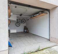 Garage space with tiles, a bicycle on the wall, and a wooden shelf.