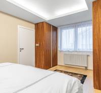 A bedroom with a wood-patterned floor, built-in wardrobe, and a window in a 4-room apartment.