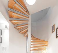 A spiral staircase with a wooden decor floor in a 4-room apartment. There are paintings on the walls.