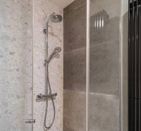 Shower corner with gray tiles in a 4-room apartment.