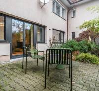 Courtyard of a 4-room apartment with outdoor seating, interlocking paving, and greenery.