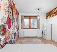A room with patterned floral wallpaper, a bookshelf, a chest of drawers, and a wooden decor floor in a 4-room apartment.