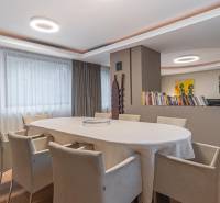 Dining room in a 4-room apartment, large oval table, wooden decor flooring, bookshelf.