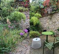 A garden with a stone fence, colorful plants, and modern seating on Tichá Street.
