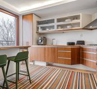 A kitchen in a 4-room apartment with wooden decor, a colorful carpet, and large windows.