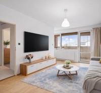 Studio apartment with wood-patterned flooring, a comfortable sofa, and a large television.