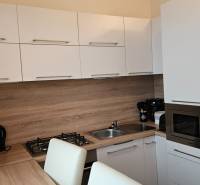 A kitchen in a 2-room apartment with white cabinets and a wood-patterned floor.