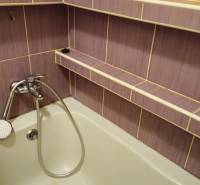 A bathroom with colorful tiles and a bathtub in a 2-room apartment.