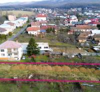 Plots - housing in Nováčany, showing houses and a church building in the background.