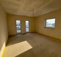 Spacious room with large windows in a family house, allowing a view of the surroundings.