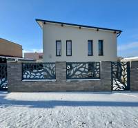 A family house in Čaňa on Gyňovská Street with a modern fence and concrete decor on the snow.