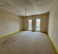 Empty room in a family house with two French windows and smooth walls.