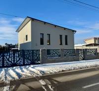 The family house on Gyňovská Street in Čaňa has a modern fence and a snowy road.