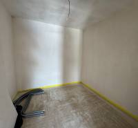 Unfinished room in a family house with wires on the floor and raw walls.