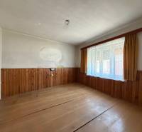 Family house with wood-patterned flooring, wall cladding, large window with lace curtains.