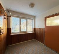The interior of a family house with paneling, large windows, and a wall-mounted coat rack.