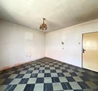 A room in a family house with a checkered floor and austere lighting.