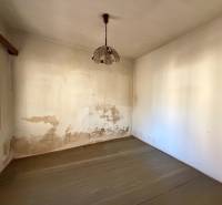 A room in a family house with a wooden decor floor and peeling walls.