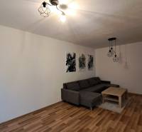 Living room in a two-room apartment with a sofa, coffee table, and floor lighting.