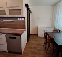 A kitchen in a 2-room apartment with wooden paneling and a dining table.