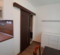 A kitchen in a 2-room apartment with sliding doors and a wooden countertop.