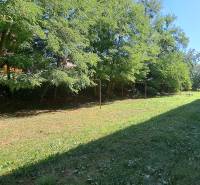 A flat grassy area with swings and trees in the town of Tlmače.