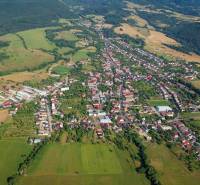 Aerial view of agricultural and forest land around Badín, surrounded by houses and buildings.